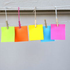 Coloured pieces of paper hanging from a line with bulldog clips