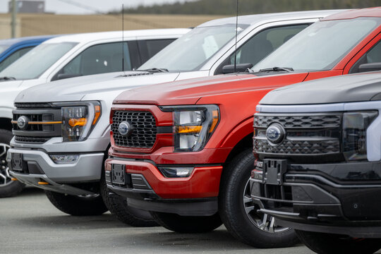 St. John's, Newfoundland, Canada-November 1, 2024: A row of Ford F-150 Ford pickup trucks. Both gasoline and electric, the new vehicles are parked on a dealership parking in a row on a lot for sale. 