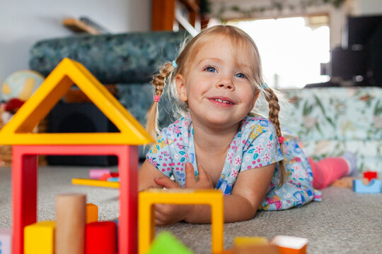Toddler girl playing with colourful blocks on floor of home