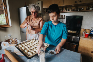 A grandmother and her grandson enjoy a baking session, making pastries together in a cozy kitchen setting.