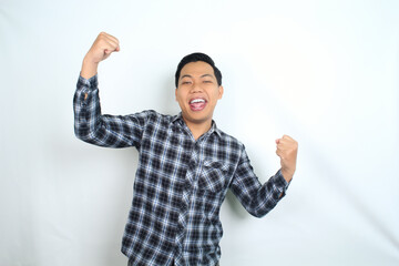 Fototapeta premium cheerful asian man raising fist showing winning and success gesture expression wearing casual shirt isolated on white