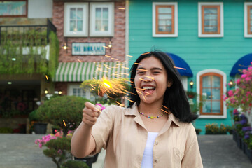 Fototapeta premium portrait of beautiful happy young asian woman holding sparklers fireworks to celebrate new year eve with garden party standing in outdoor vintage house yard