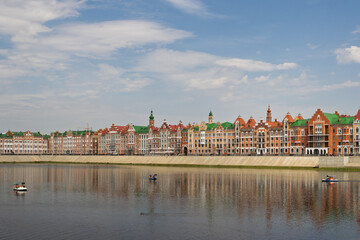 Obraz premium Yoshkar-Ola city, Mari El Republic, Russia. View of the Malaya Kokshaga River and the Brugge embankment in the center of Yoshkar-Ola. Beautiful colorful buildings on the river bank.