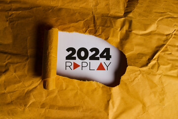 2024 Replay - A piece of torn yellow paper with the text 