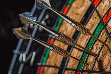 metal-tipped darts stuck in a competition cork dartboard
