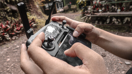 A close-up shot of a person's hands operating a drone's remote controller.