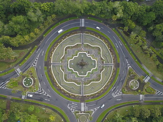 Aerial view of a roundabout with a central monument, lush green trees, and a large resort complex...