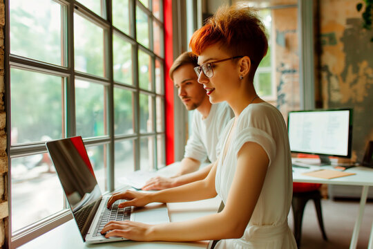 Creative coworkers working on laptops in industrial office