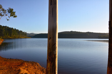 Clear, calm waters stretch beneath a vibrant blue sky at the lake's edge. The serene atmosphere captures the natural beauty of a sunny day, with gentle reflections on the water