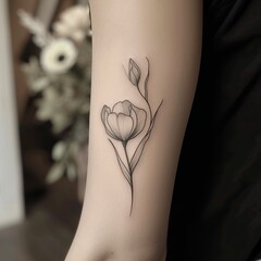 Delicate linework tattoo of a tulip on a woman's forearm. Minimalist floral ink, subtle grayscale shading.