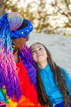 Torres Strait Islander nine year old boy with long hair sitting beside grandmother on beach