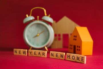 New Year, New Home, with an alarm clock, miniature houses, and wooden blocks spelling out 