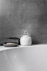 Natural magnesium salt in glass jar, soap, exfoliating loofah, gray bathroom, concrete background....