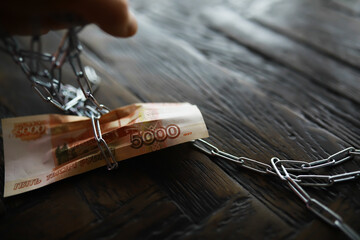Russian Banknotes Chained Down on Wooden Table Reflecting Financial Constraint Concept