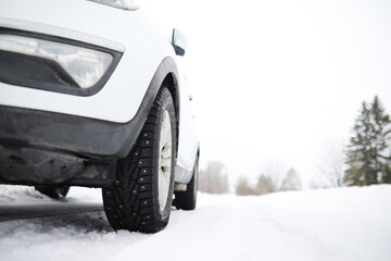 White Car Driving in Snowy Winter Landscape, Close-Up of Tire on Snow-Covered Road
