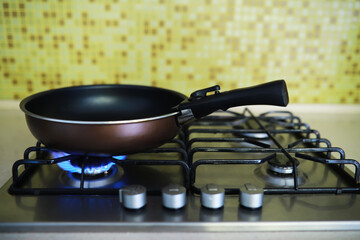 Modern Non-Stick Frying Pan on Gas Stove with Lit Burner in Home Kitchen