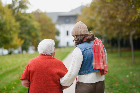 Rear view of a granddaughter on an autumn walk in the park with her grandmother.