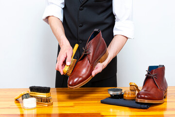 Footwear Concepts and Ideas. Hands of Professional Caucasian Male Shoes Cleaner with Cleaning Cloth...