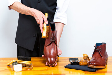 Footwear Concepts and Ideas. Hands of Professional Caucasian Male Shoes Cleaner with Cleaning Brush...