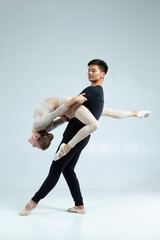 Professional International Sportive Couple of Asian Man and Caucasian Woman Performing As Ballet Dancers Over Grey in Studio During Suppots © danmorgan12