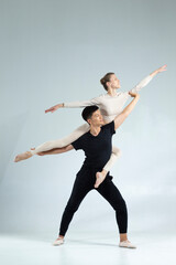 One Sportive Couple of Asian Man and Caucasian Woman Performing As Ballet Dancers Over Grey in Studio During Suppots in Classical Dance © danmorgan12