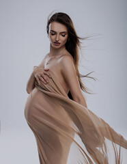Fototapeta premium beautiful pregnant woman in studio with light drapery like virgin mary