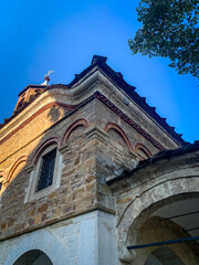 The facade of Saint Nikola Church in Dryanovo, Bulgaria, features distinctive stone and brick architecture with arched windows and a cross atop the roof.
