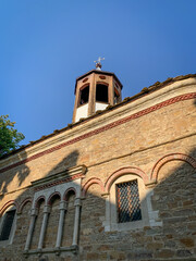 The weathered stone facade of the Saint Nikola church in Dryanovo, Bulgaria, with its distinctive arched windows and a small belfry, evokes a sense of timeless beauty and historical significance. 