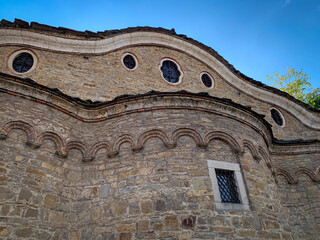 The intricate stonework and distinctive rounded arches of the Saint Nikola church in Dryanovo, Bulgaria, create a captivating architectural tapestry against the backdrop of a clear blue sky.
