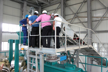 Man worker in safety helmet working on steel machine