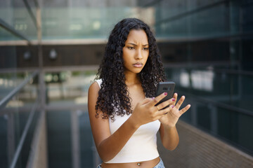 A young woman is completely engrossed in her smartphone as she messages outside during the day