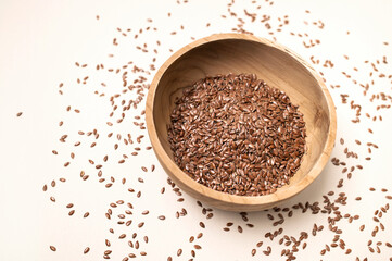 Fresh raw natural organic flax seeds in wooden bowl on beige light background top view. Healthy eating, superfood, eco-friendly brown flax seeds. Healthy fats and vitamins