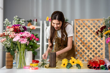 Asian young florist girl completing beautiful bouquet in flower shop.