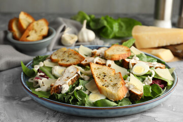 Tasty Caesar salad with chicken on gray textured table, closeup