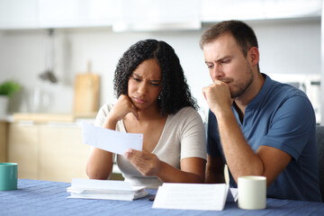 Worried interracial couple checking bank statement