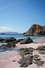 Rocky Shore of Pink Beach, Reef and Hilltop in Background