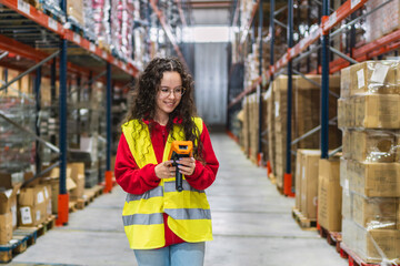 Young female warehouse worker scanning packages with barcode scanner