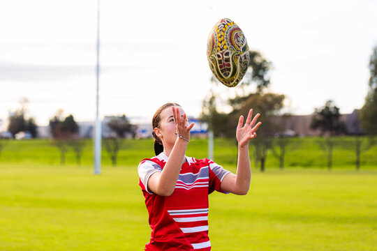 Teen female Australian rules football player throwing footy ball