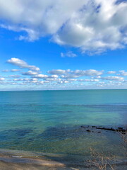 Obraz premium Panorama of a cloud flock illuminated by the autumn sun in the blue sky circling over the azure Odessa coast.