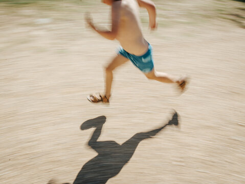 Boy running in swimmers with shadow and motion blur