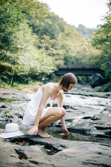Fototapeta premium A serene woman peacefully standing by the tranquil stream immersed in the beauty of nature