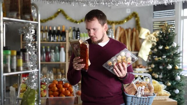 Man with soft nutty nougat and sweet traditional Catalan desserts panellets in a Christmas supermarket. Buyer chooses European sweets for the New Year. High quality 4k footage