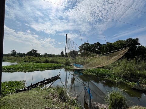 Fishing net in the pond with a boat and Clouds in the sky in Majuli island Assam