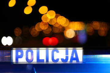 Sygnalizator błyskowy niebieski na dachu radiowozu policji polskiej w nocy.