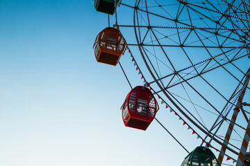 From below static ferris wheel against a clear blue sky, showcasing its symmetry and colorful...