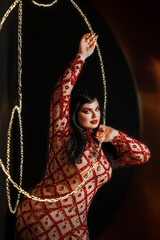 A beautiful young girl plus size model in a red evening dress with bright makeup with a snake. New Year's photo shoot with a snake