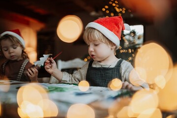 Siblings making holiday Christmas cards for family. Children painting pictures for Santa Claus or...