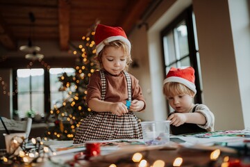 Siblings making holiday Christmas cards for family. Children painting pictures for Santa Claus or...