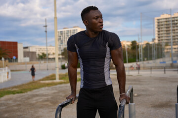 Young black man doing calisthenics exercises in urban environment