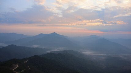 Morning view from the top of the mountain as the sun rises covered in mist created by the steam of the river below